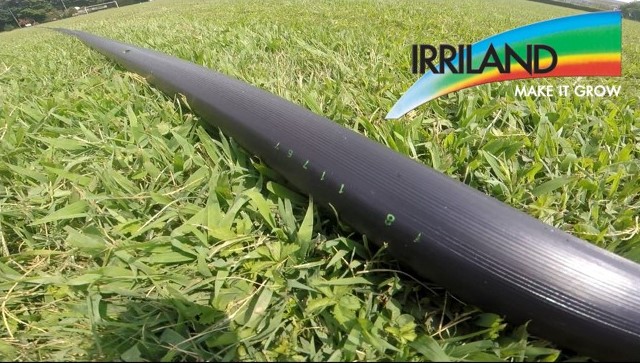 Tubo Irrigatore Irriland steso Immagine di un campo con erba ed un tubo per irrigazione